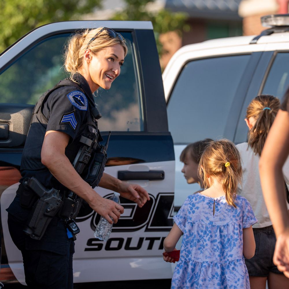 A South Jordan City Police Officer interacting with the community at an event and police vehicle